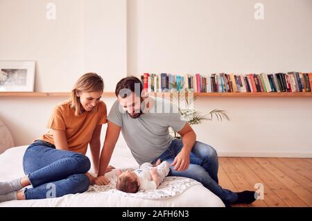 Les parents aimants avec nouveau-né Baby Lying On Bed At Home in Loft Apartment Banque D'Images