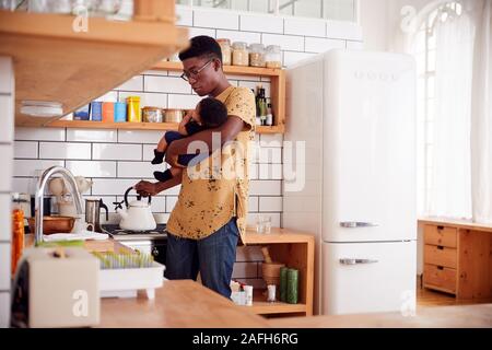 Multitâche Père Fils Bébé détient et se déverse dans la cuisine électrique Banque D'Images