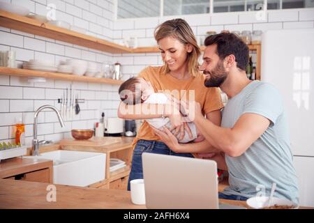 Famille occupée dans la cuisine au petit-déjeuner avec la mère s'occuper de son bébé Banque D'Images