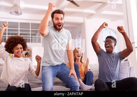 Heureux Groupe d'amis assis sur le canapé à regarder le sport à la télévision et à célébrer Banque D'Images