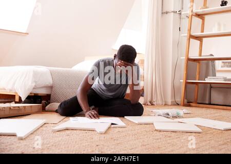 Homme frustré dans nouvelle maison Mettre Ensemble de meubles à assembler soi-même Banque D'Images