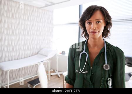 Portrait Of Smiling Female Doctor with Stethoscope Standing By Desk In Office Banque D'Images