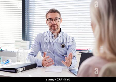 Femelle adulte Patient en consultation avec Doctor Sitting At Desk In Office Banque D'Images