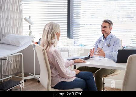 Femelle adulte Patient en consultation avec Doctor Sitting At Desk In Office Banque D'Images