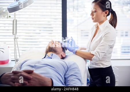 Coiffeur femme mature donnant Male Patient injection de Botox Dans le Front Banque D'Images