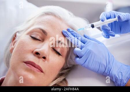 Femelle adulte donnant coiffeur injection de Botox dans le front du patient Banque D'Images