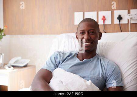 Portrait Of Male Patient Lying in Hospital Bed Smiling at Camera Banque D'Images