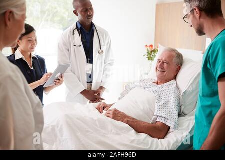 L'équipe médicale sur Tours rencontre autour du lit Senior Male Patient Banque D'Images