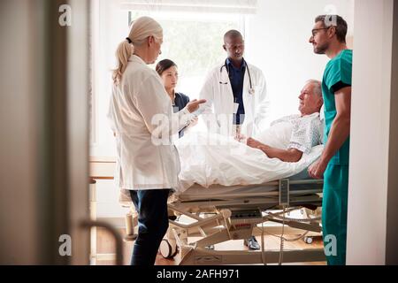 L'équipe médicale sur Tours rencontre autour du lit Senior Male Patient Banque D'Images