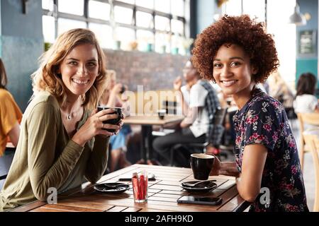 Portrait de deux Amies Séance Sitting At Table in Coffee Shop Banque D'Images