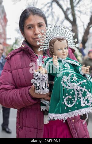 Une femme catholique américain équatorien dans un milieu décembre mars avec une statue de l'Enfant Jésus pour célébrer la naissance du Christ. À Corona, Queens, New York. Banque D'Images