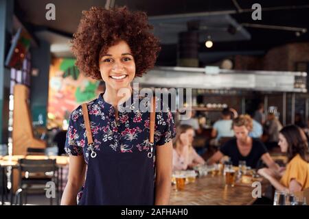 Portrait Of Waitress Serving in Busy Bar Restaurant Banque D'Images
