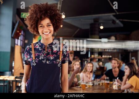 Portrait Of Waitress Serving in Busy Bar Restaurant Banque D'Images