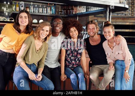 Portrait Of Male and Female Friends Sitting par compteur dans Sports Bar Banque D'Images