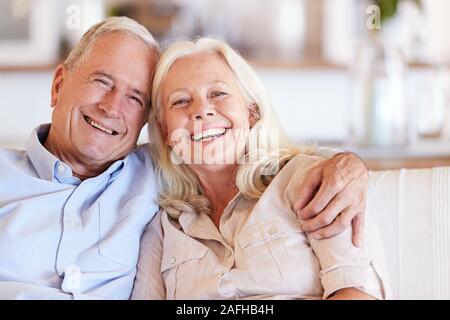 Happy senior couple blanc assis à la maison et pour faire place au sourire de l'appareil photo, vue de face, Close up Banque D'Images