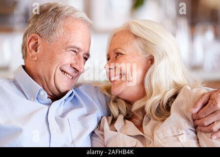 Happy senior couple assis à la maison blanche, embrassant, tête et épaules, Close up Banque D'Images