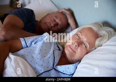 Blanc Senior couple lying endormis dans leur lit, jusqu'à la taille, Close up Banque D'Images