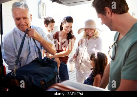 Grand-père et père de démarrage voiture d'emballage de vacances avec assurance, tandis que la famille d'attendre à proximité, Close up Banque D'Images