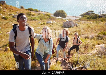 African American man millénaire menant amis randonnées seul fichier en montée sur un chemin par la côte Banque D'Images