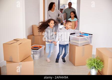 Smiling Family Carrying Boxes dans nouvelle maison le jour du déménagement Banque D'Images