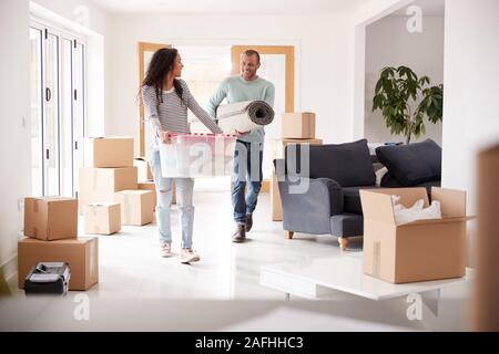 Smiling Couple Carrying Cases dans nouvelle maison le jour du déménagement Banque D'Images