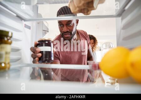 À la vue de l'intérieur du réfrigérateur en Couple Ouvrez la porte et déballez votre sac de nourriture Banque D'Images