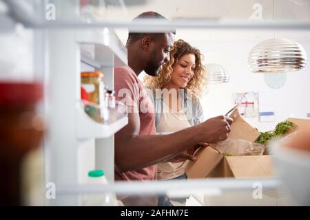 À la vue de l'intérieur du réfrigérateur en Couple Déballez en ligne Accueil Livraison de nourriture Banque D'Images