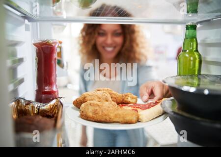 À la vue de l'intérieur du réfrigérateur rempli d'aliments à emporter comme femme ouvre la porte Banque D'Images