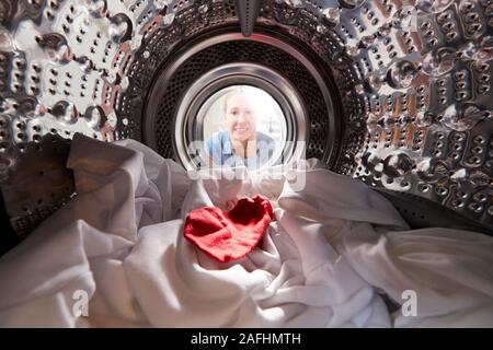 Femme à l'intérieur d'un lave-linge avec Chaussette rouge blanc mélangé avec une laverie Banque D'Images