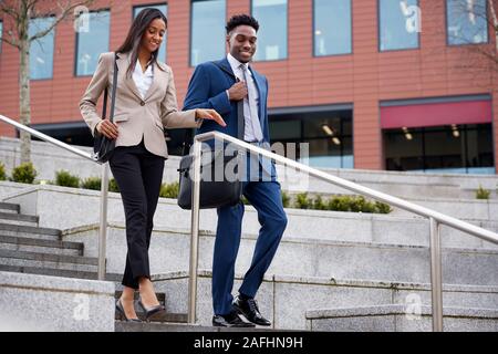 Businessman And Businesswoman déplacements quotidiens au travail Walking Down Steps Outside Office Building Banque D'Images