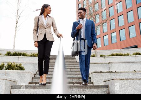 Businessman And Businesswoman déplacements quotidiens au travail Walking Down Steps Outside Office Building Banque D'Images