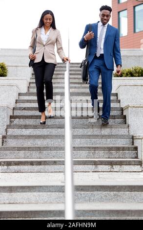 Businessman And Businesswoman déplacements quotidiens au travail Walking Down Steps Outside Office Building Banque D'Images