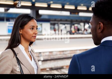 Businessman And Businesswoman pour se rendre à son travail en conversation sur un quai de gare en attente de Train Banque D'Images