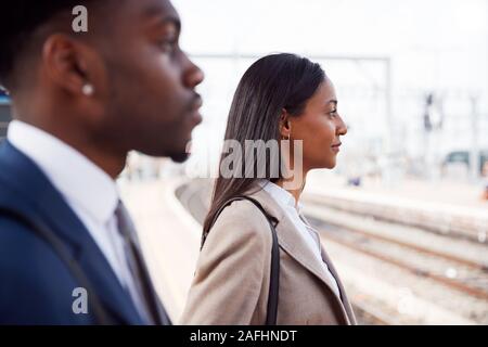 Businessman And Businesswoman pour se rendre à son travail sur un quai de gare en attente de Train Banque D'Images