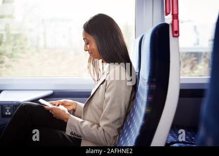 Businesswoman Sitting in Train pour se rendre à son travail de la consultation des messages sur téléphone mobile Banque D'Images