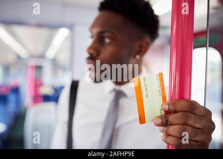 Businessman Standing In Train pour se rendre à son travail Holding Ticket Banque D'Images