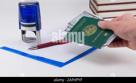 Mains courantes sur le passeport de l'Ouzbékistan avec des dollars américains sur la base de documents et de timbres en caoutchouc. Concept - corrupteur et la corruption Banque D'Images