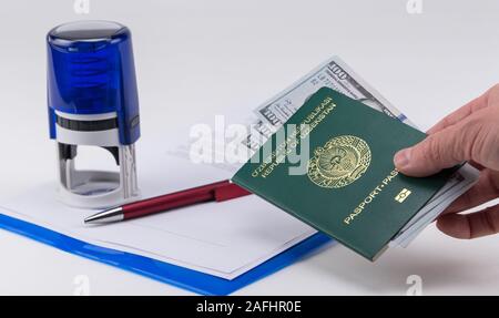 Mains courantes sur le passeport de l'Ouzbékistan avec des dollars américains sur la base de documents et de timbres en caoutchouc. Concept - corrupteur et la corruption Banque D'Images