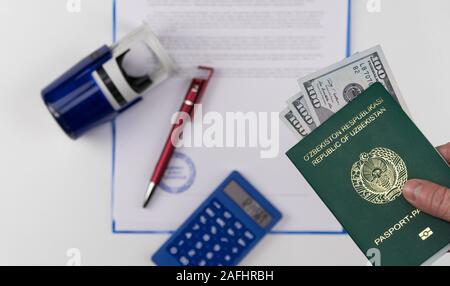 Mains courantes sur le passeport de l'Ouzbékistan avec des dollars américains sur la base de documents et de timbres en caoutchouc. Concept - corrupteur et la corruption Banque D'Images
