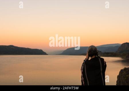 Une jeune femme avec poncho sur le coucher du soleil prend des photos à la Corbett lookout sur le fleuve Columbia, New York Banque D'Images