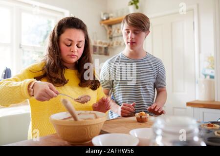 Les jeunes Trisomie Couple Decorating Cupcakes fait maison avec du glaçage dans la cuisine à la maison Banque D'Images