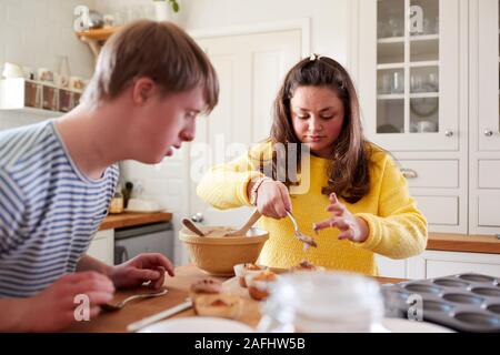 Les jeunes Trisomie Couple Decorating Cupcakes fait maison avec du glaçage dans la cuisine à la maison Banque D'Images