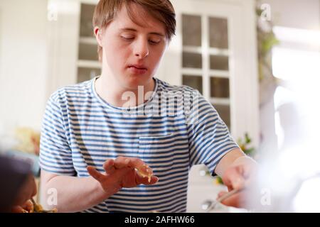 Jeune homme Trisomie Baking Cupcakes dans la cuisine à la maison Banque D'Images