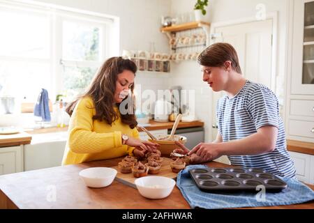 Les jeunes Trisomie Couple Decorating Cupcakes fait maison avec du glaçage dans la cuisine à la maison Banque D'Images