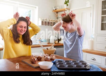 Les jeunes Trisomie Couple Decorating Cupcakes fait maison avec des guimauves dans la cuisine à la maison Banque D'Images