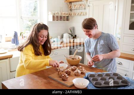 Les jeunes Trisomie Couple Decorating Cupcakes fait maison avec des guimauves dans la cuisine à la maison Banque D'Images