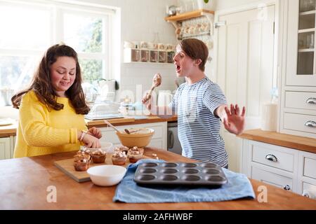 Les jeunes Trisomie Couple Decorating Cupcakes fait maison avec des guimauves dans la cuisine à la maison Banque D'Images