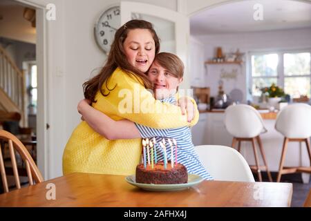 Les jeunes couples célébrant le syndrome de Down à la maison d'anniversaire avec gâteau Banque D'Images