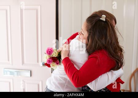 Aimer les jeunes Trisomie Couple Sitting on Bed With Man Giving Woman Flowers Banque D'Images