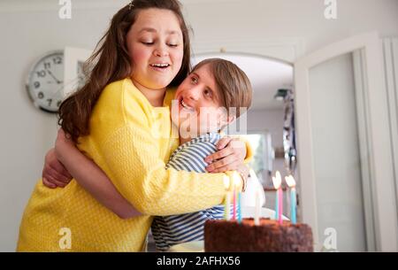 Les jeunes couples célébrant le syndrome de Down à la maison d'anniversaire avec gâteau Banque D'Images
